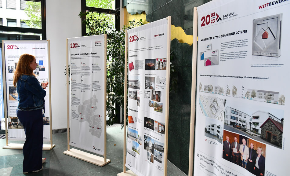 Frau vor Ausstellungsbannern der Ausstellung 20 Jahre Baukultur Rheinland-Pfalz